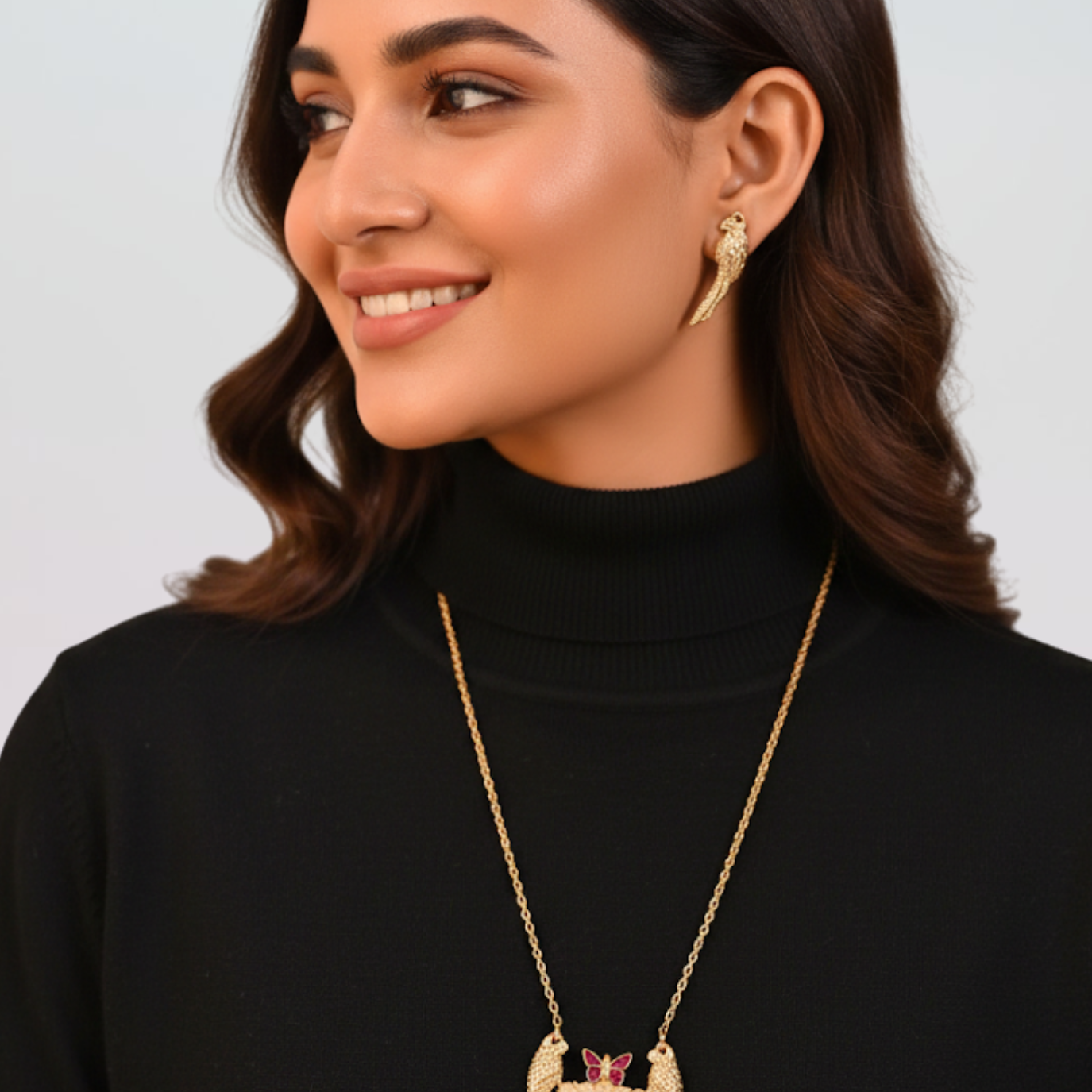 Woman wearing a gold necklace and earrings against a plain background