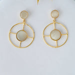 Gold hoop earrings with circular designs on a light background

