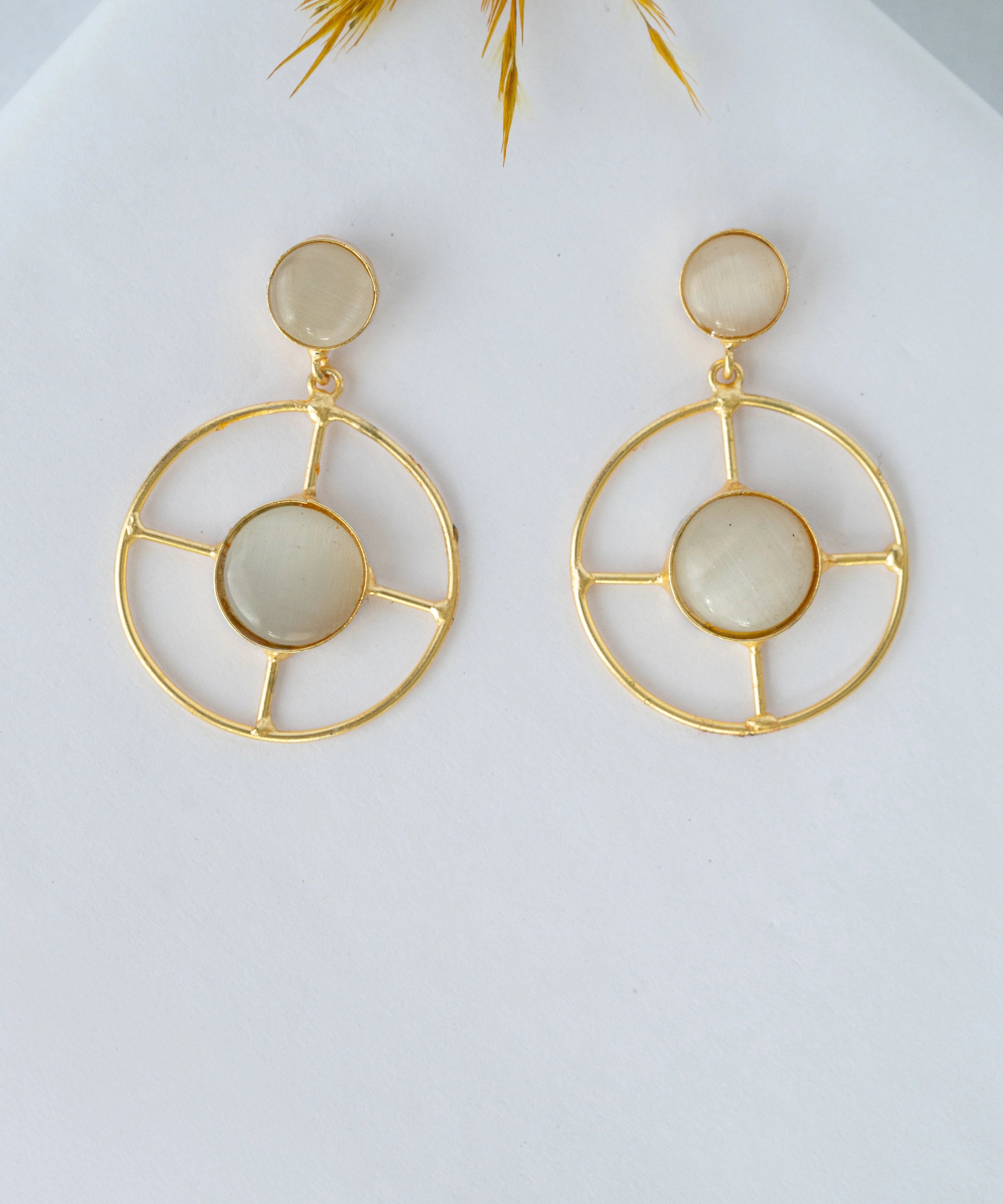 Gold hoop earrings with circular designs on a light background


