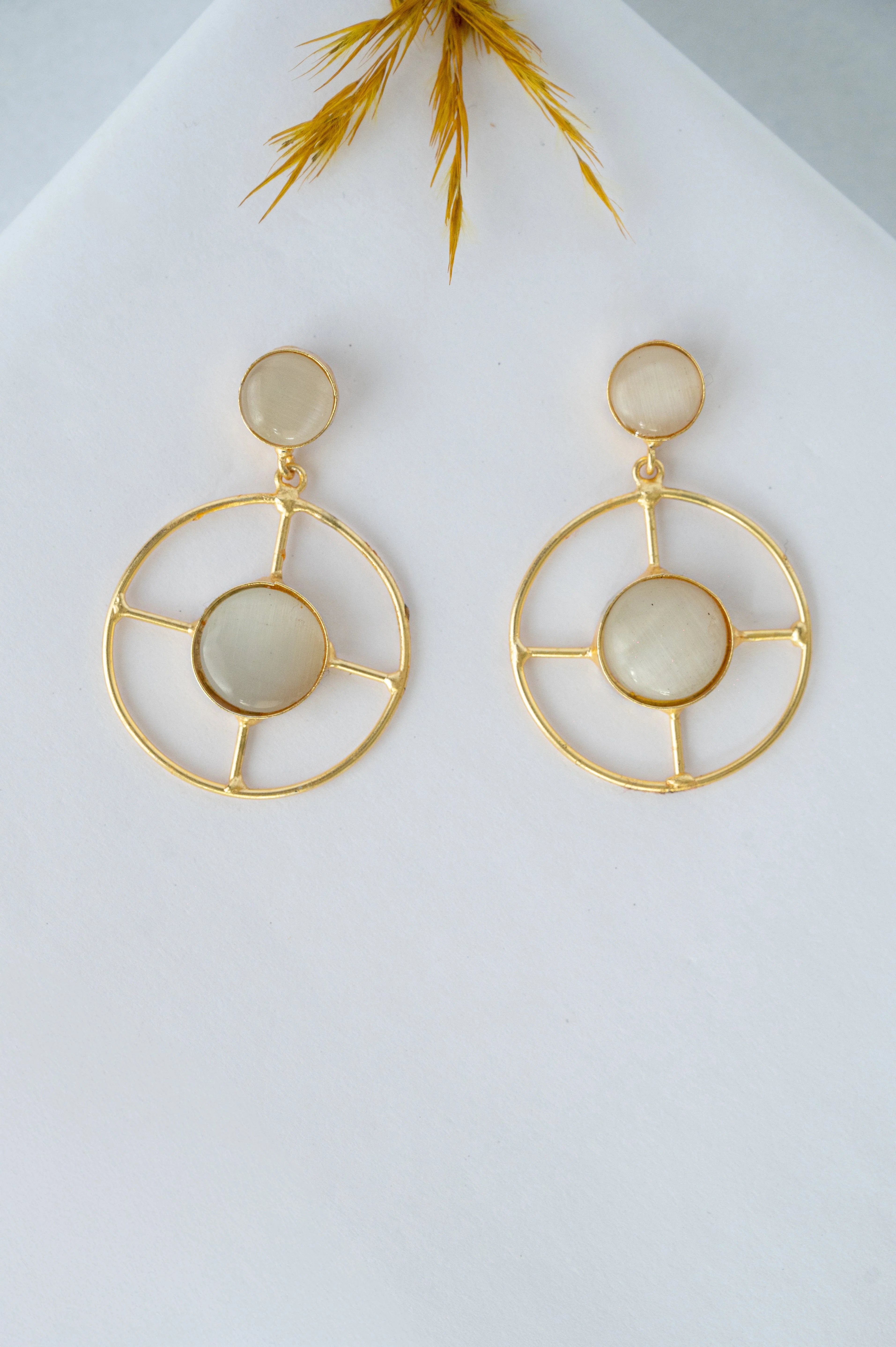 Gold hoop earrings with circular designs on a light background

