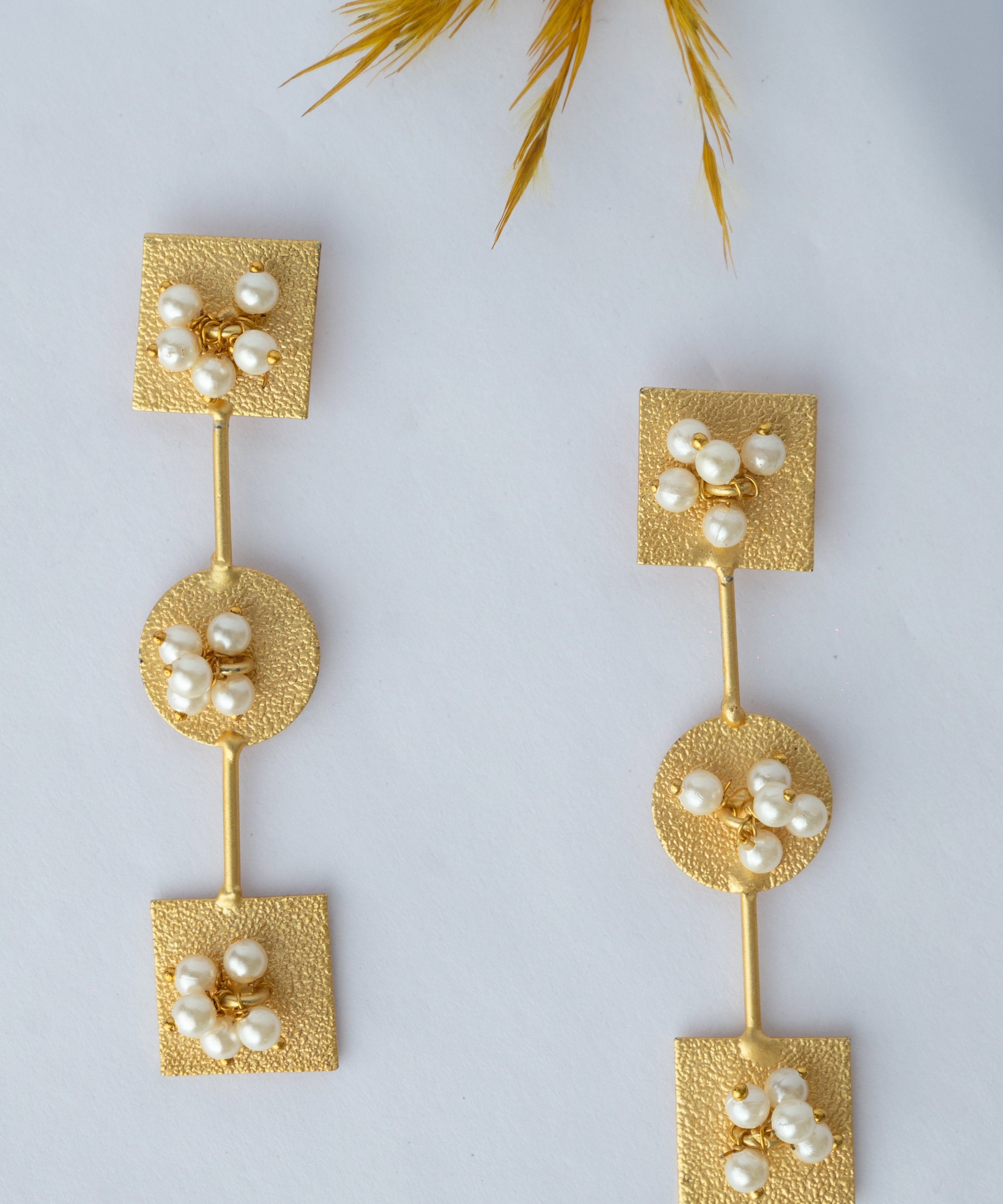 Pair of gold earrings with pearls on a light gray background