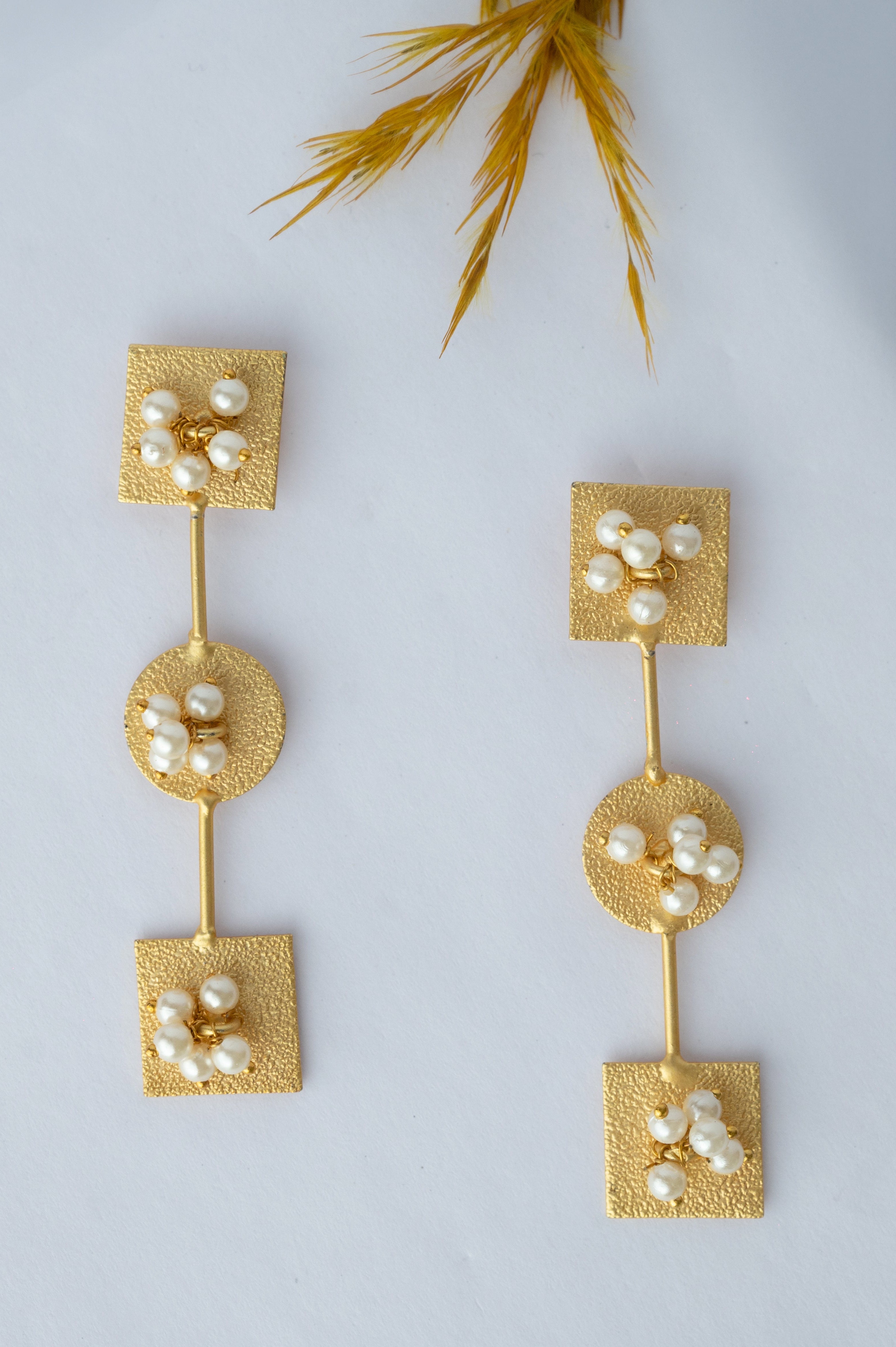 Pair of gold earrings with pearls on a light gray background