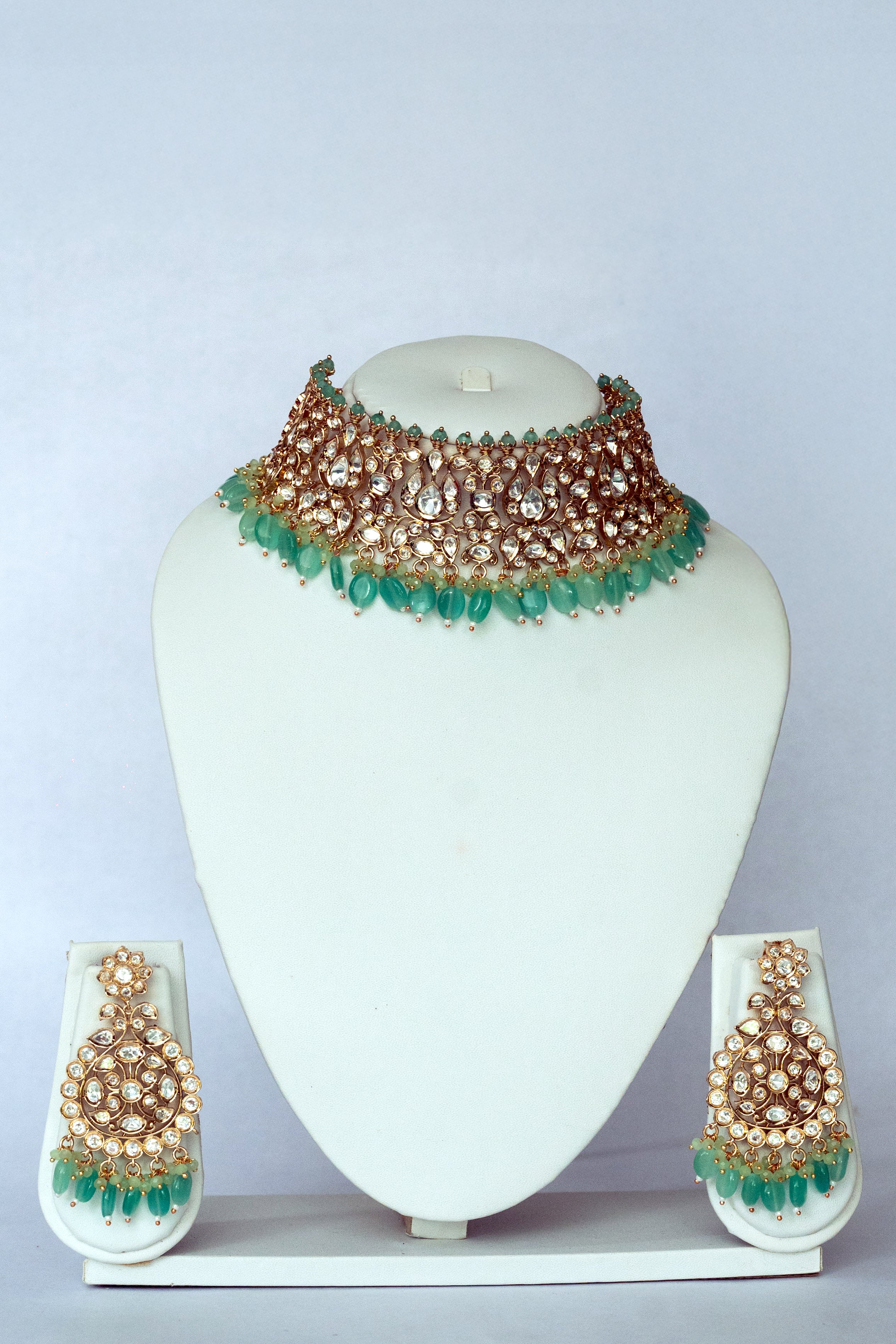 Jewelry set with necklace and earrings on a white stand against a light gray background