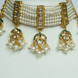 Pearl necklace with gold and green accents on a white background