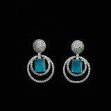 Pair of earrings with blue stones and silver circular designs on a black background

