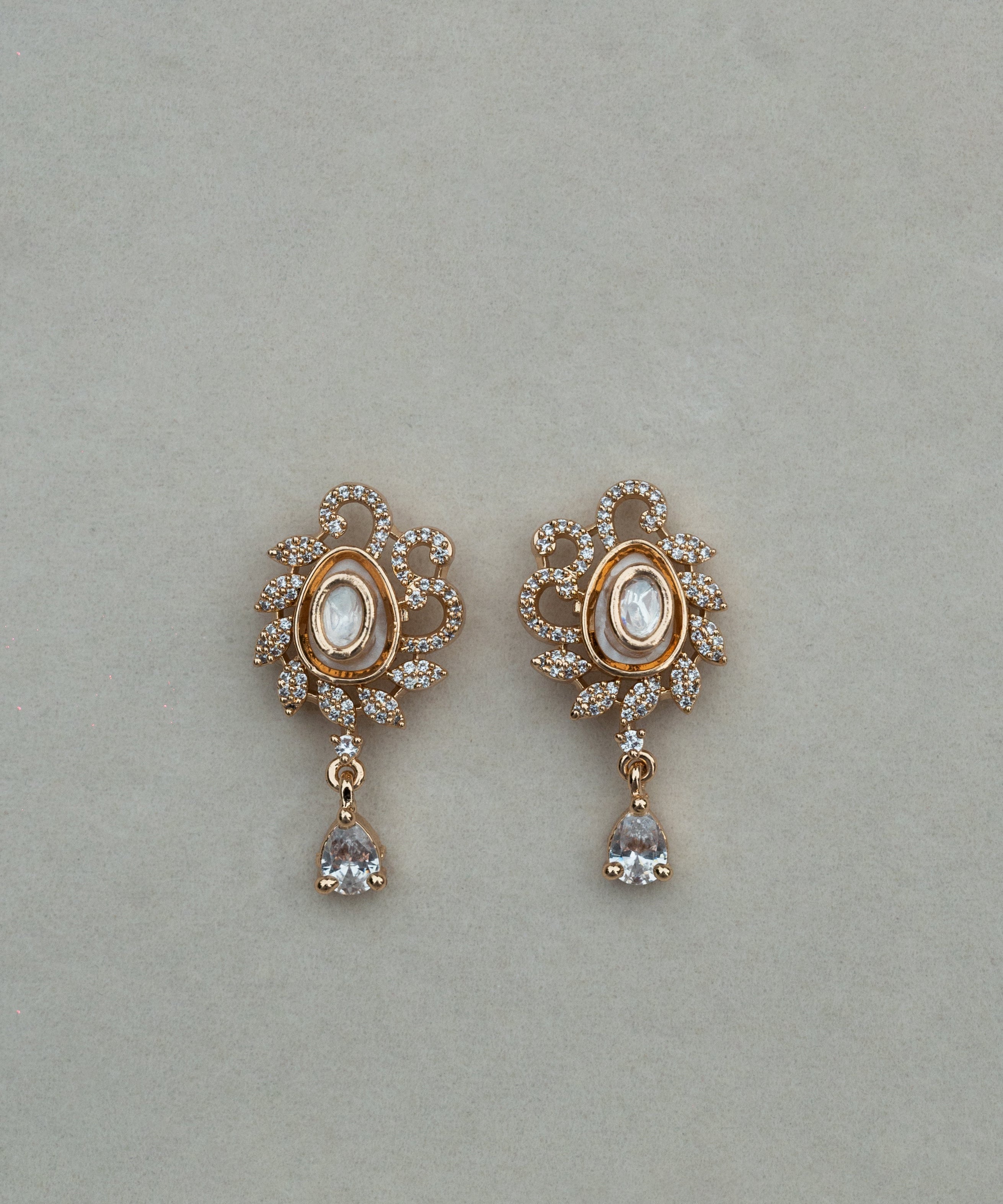 Pair of gold earrings with gemstones on a light gray background