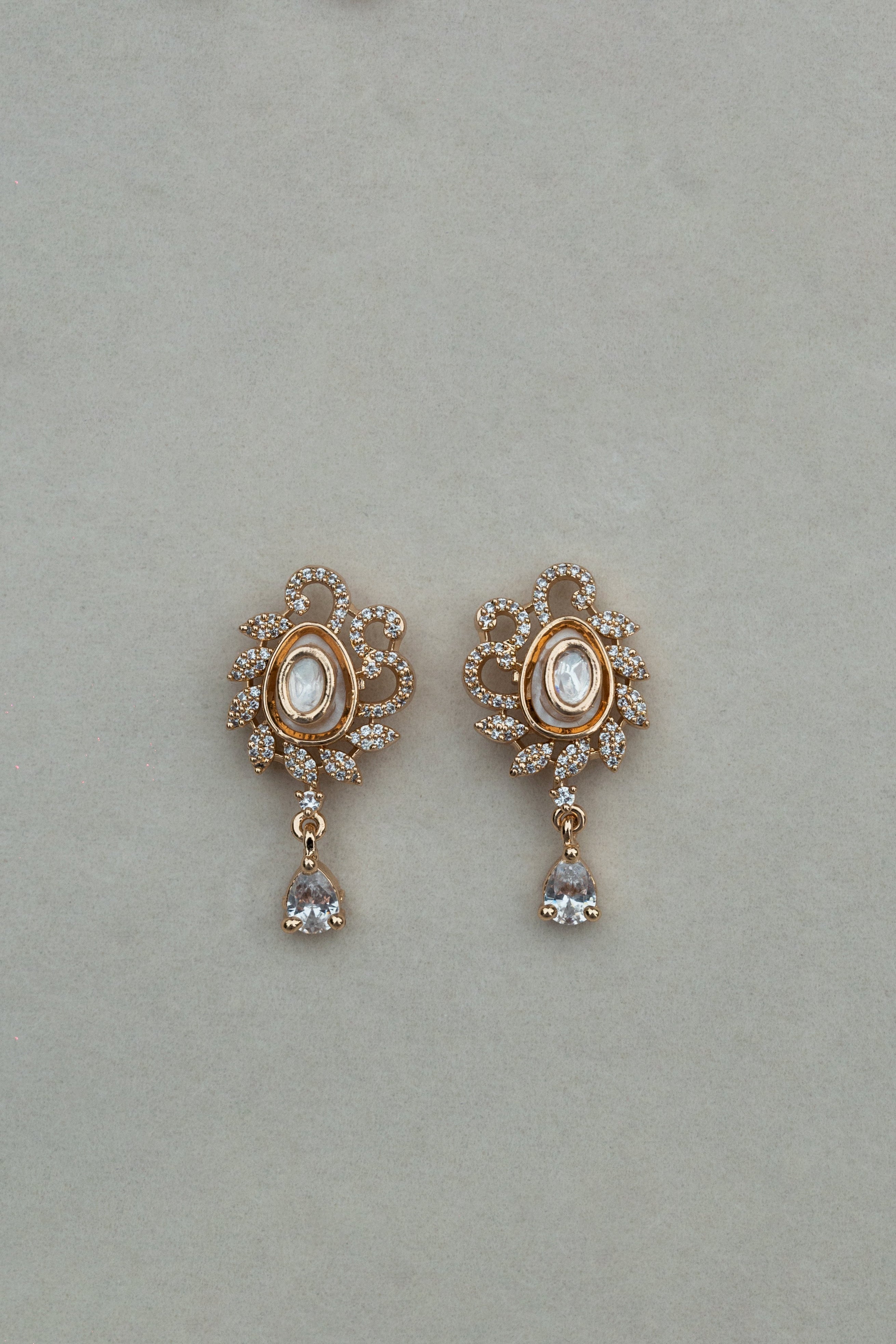 Pair of gold earrings with gemstones on a light gray background
